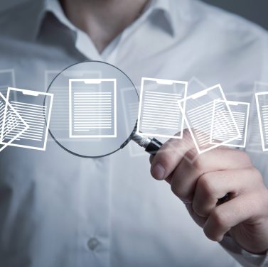 Man holding magnifying glass with a documents.